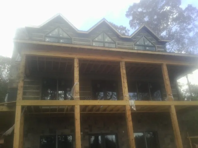 Dormers and porch framing on a large log home under construction — Roof Coating work by our crew in North Jackson