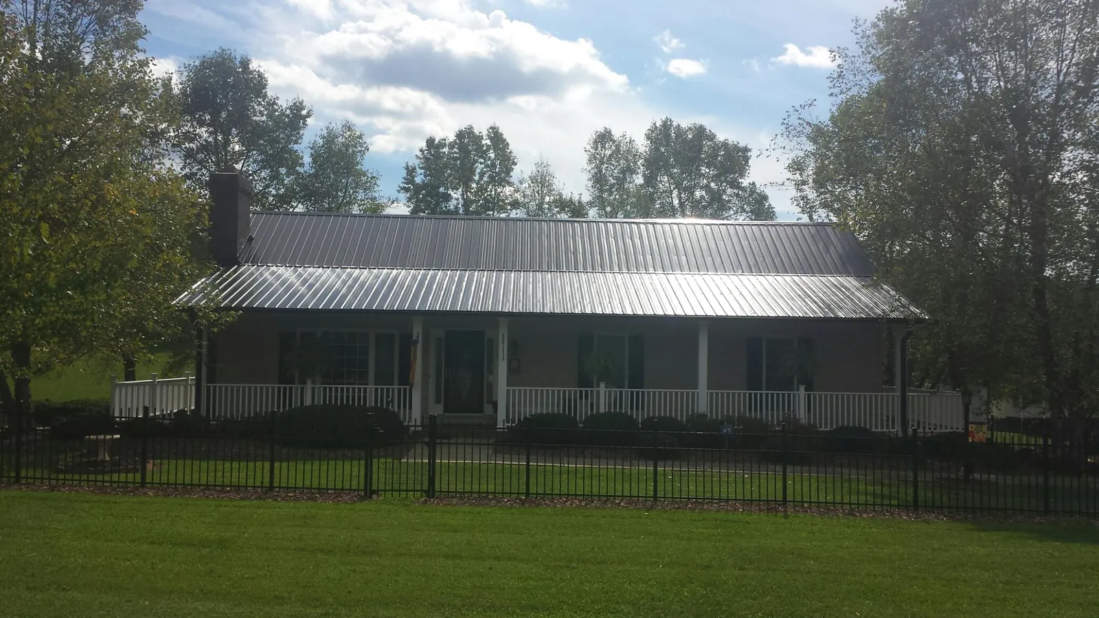 Gray metal roof on a brick ranch with a full width front porch — Gutter Guard Installation work by our crew in North Jackson
